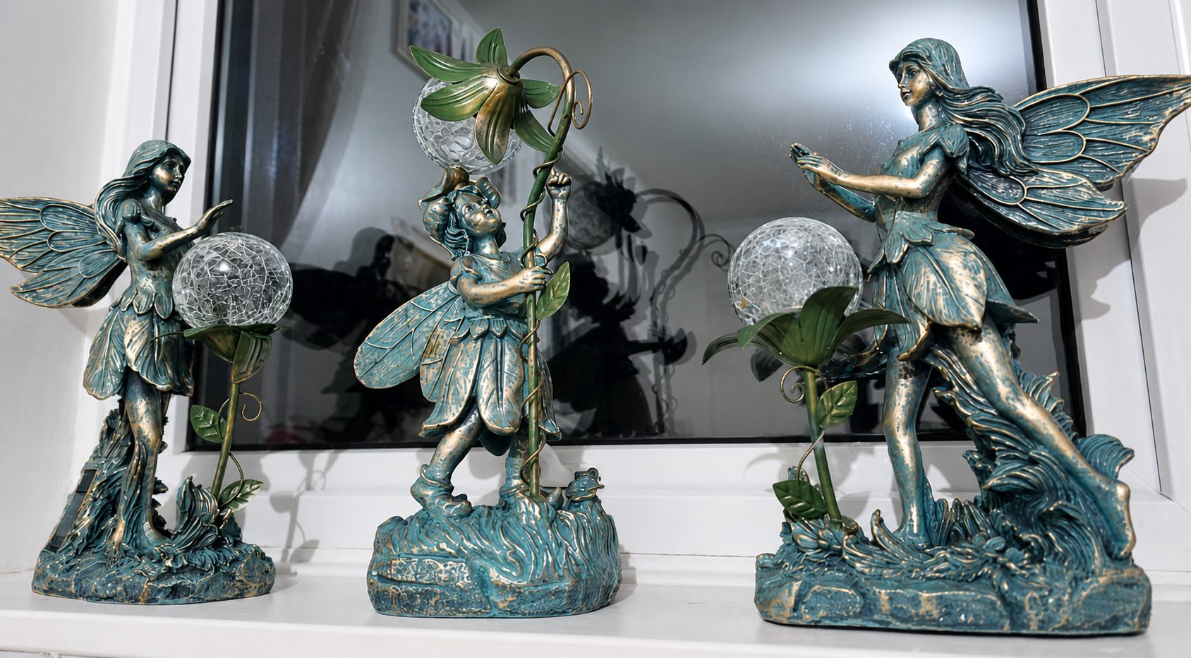 Three decorative fairy statues displayed together