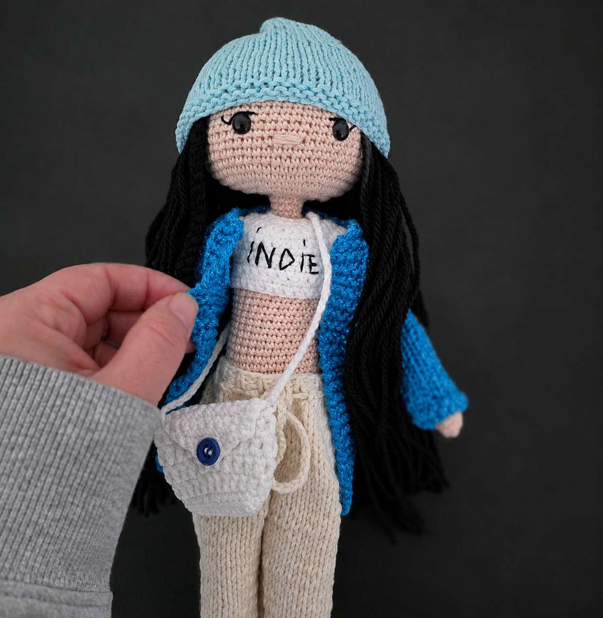 Close-up handmade crochet doll with blue hat and bag