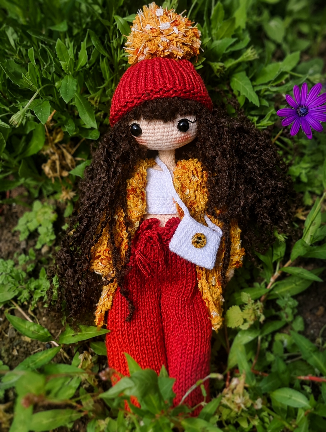 Handmade crochet doll photographed among garden greenery